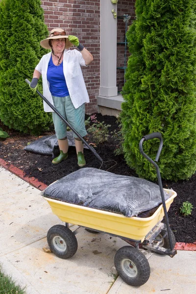 Senior woman working in the garden mulching — Stock Photo, Image