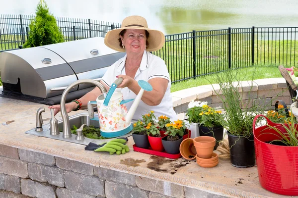 Friendly elderly lady watering her houseplants — Stock Photo, Image