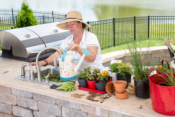 Lady filling a watering can on an outdoor patio