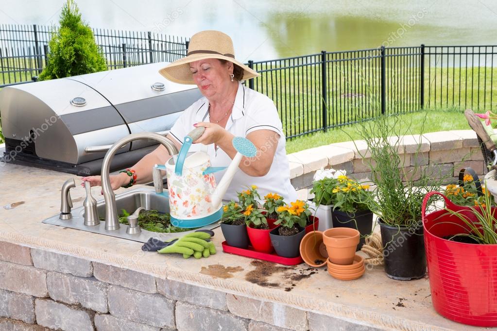 Lady filling a watering can on an outdoor patio