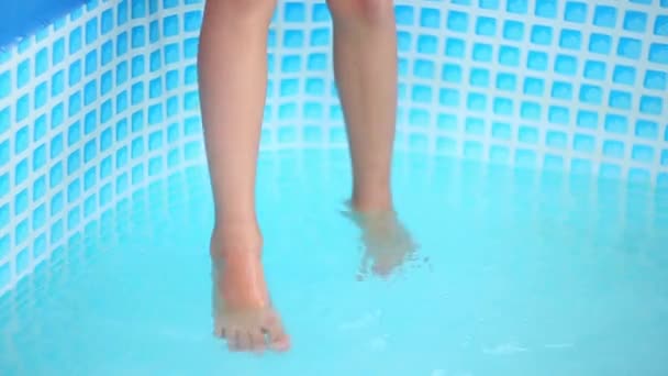 那孩子坐在游泳池上 把他的腿挂在水里 夏天在炎热中快乐 — 图库视频影像