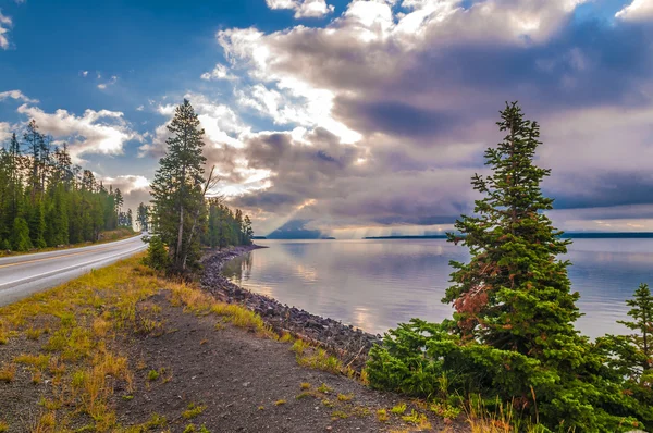 Road in Yellowstone and Rays of Light over the lake — Stock Photo, Image