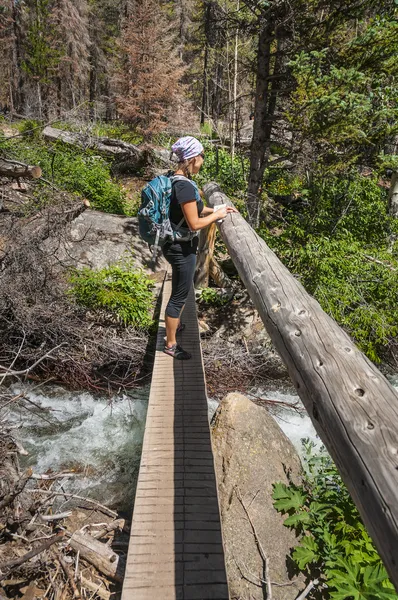 Hiker crossing a footbridge on the trail — Stock Photo, Image