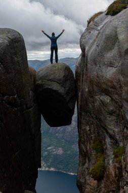 Zafer pozu Kjeragbolten 'in tepesinde. Dağın yarığına sıkışmış kaya parçası. Denizden 984 metre yukarıda.