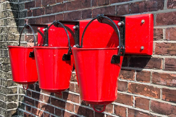Drie rode brand emmers muur gemonteerd — Stockfoto
