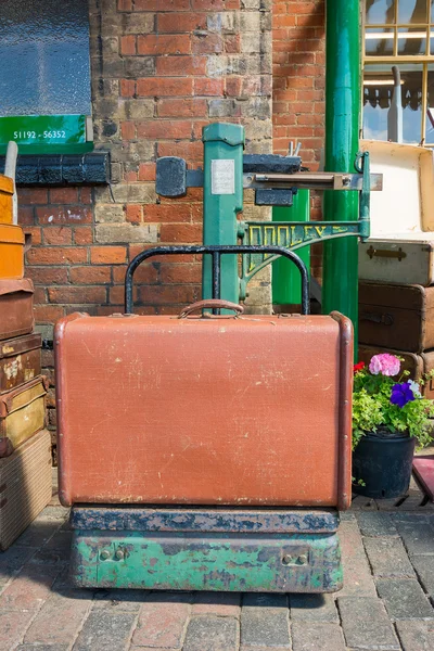 Old suitcase on vintage weighing scales — Stock Photo, Image
