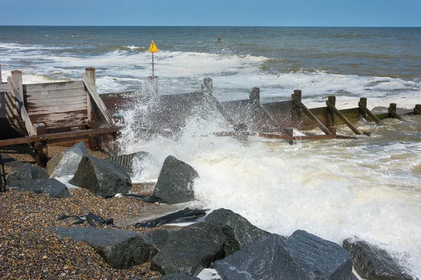 Waves breaking onto a shingle beach with groynes — Stock Photo, Image