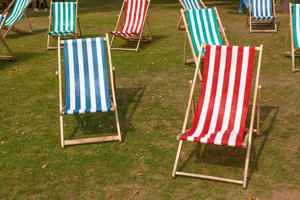 Canvas deckchairs on a grassy lawn in the summer. — Stock Photo, Image