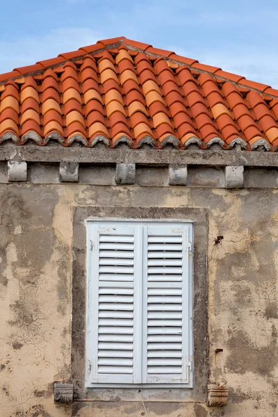 Edifício com telhas laranja e janela wodden obturado — Fotografia de Stock