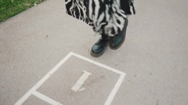 市内の遊び場でホッチング若い女性のクローズアップ 歩道に描かれたセルに飛び乗る少女の足の閉鎖 — ストック動画