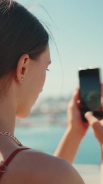 Yakından çekilen sevimli kız, limanın videolarını bir cep telefonuyla çekiyor. Kız yat ve gemi vururken akıllı telefondan sosyal ağlar ve yayın hizmetleri kullanıyor.