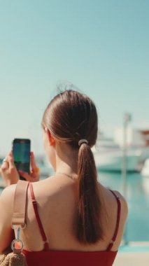 Yakından çekilen sevimli kız, limanın videolarını bir cep telefonuyla çekiyor. Yatlara ve gemilere ateş ederken sosyal ağlar ve akıllı telefonlardan yayın yapan bir kız. Arka plan