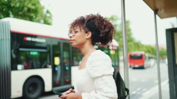 Ung Kvinna Glasögon Med Ryggsäck Väntar Stadstransport Stående Vid Busshållplatsen — Stockvideo