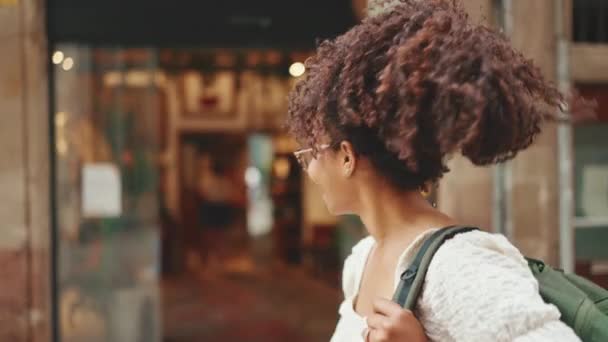 Sırt Çantalı Gözlüklü Gülümseyen Genç Bir Kadın Şehir Merkezinde Yürüyor — Stok video