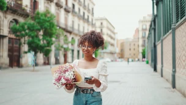 Gözlüklü Genç Bir Kadın Elinde Çiçeklerle Eski Şehrin Caddesinde Yürüyor — Stok video