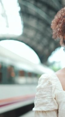 Gözlüklü, çantalı genç bir kadının yakından çekilmiş portresi trenden iniyor ve istasyonda yürüyor. Çantalı kız trenden inip istasyondan geçiyor.