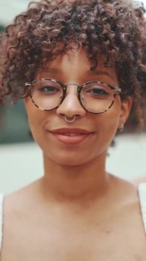 Kameraya bakarken gülümseyen gözlüklü genç bir kadının yakın plan portresi. Mutlu bir kızın portresi