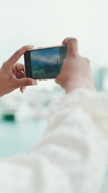 Gözlüklü genç bir kadının yakın plan portresi rıhtımda duruyor ve akıllı telefondan gemilere bakıyor ve ateş ediyor. Şehir arka planında cep telefonu kullanan bir kıza yakın çekim