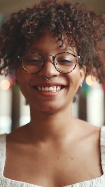 垂直录像 一个戴着眼镜的年轻女子在镜头前微笑的特写 一个快乐女孩的画像 — 图库视频影像