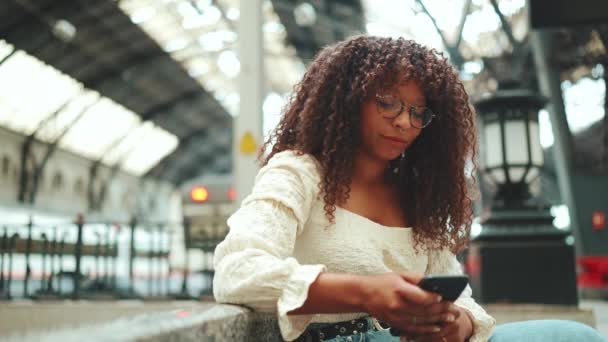 Close Uma Jovem Mulher Óculos Senta Estação Olha Para Smartphone — Vídeo de Stock