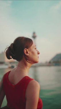 Yakından bakınca, kız setin üzerinde duruyor ve körfeze doğru bakıyor. Genç bir kadının yakından çekilmiş portresi sabah denize bakıyor..