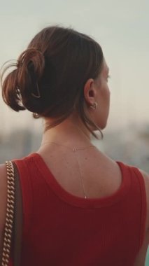 Yakından bakınca, kız setin üzerinde duruyor ve cep telefonuyla güneşin doğuşunun fotoğraflarını çekiyor. Genç bir kadın, sabahları akıllı telefonuyla denizi vuruyor. Arka plan