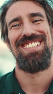 Toprağın üzerinde sakallı, gülümseyen bir adamın yakın plan portresi. Kameraya bakan mutlu genç hipster erkeğin ön yakın plan portresi