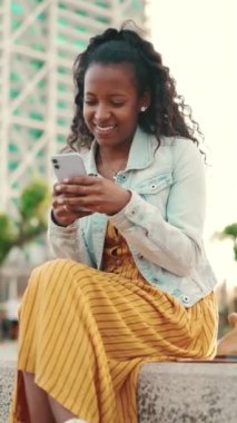 Şehirdeki bir arka planda cep telefonu kullanan uzun kıvırcık saçlı genç bir kadının yakın çekimi. Sosyal ağlarda gezinen, internetten alışveriş yapan kızlara yakın çekim