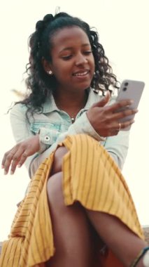 Şehirdeki bir arka planda cep telefonu kullanan uzun kıvırcık saçlı genç bir kadının yakın çekimi. Sosyal ağlara girip internetten alışveriş yapan bir kızın yakın plan fotoğrafı.