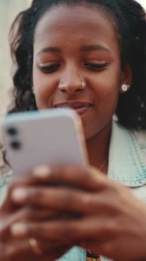 Gökyüzü arka planında cep telefonu kullanan uzun kıvırcık saçlı genç bir kadının yakın çekimi. Sosyal ağlara girip internetten alışveriş yapan bir kızın yakın plan fotoğrafı.
