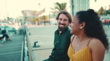 Limanda oturan mutlu ırklar arası çiftin yakın çekimi. Yakından geçen yatların önünde konuşan ve gülümseyen genç bir aile.