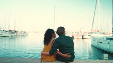 Limanda oturan mutlu ırklar arası çiftin yakın çekimi. Yakından, genç kadın ve erkek kucaklaşması. Arka plan
