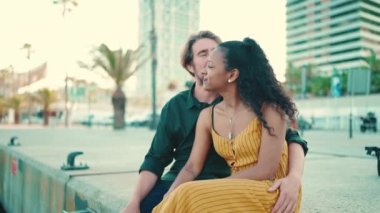 Limanda oturan mutlu ırklar arası çiftin yakın çekimi. Yakın plan, arka plandaki yatlarda sarılıp öpüşen genç aile.