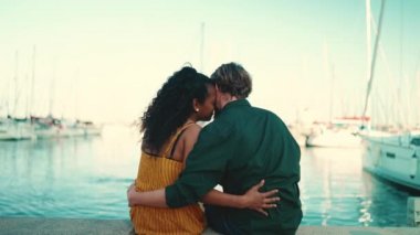 Limanda oturan mutlu ırklar arası çiftin yakın çekimi. Yakın plan, arka plandaki yatların dışında genç aile öpüşmeleri. Arka plan