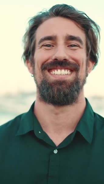 垂直录像 一个留着胡子的微笑男子在路堤上的特写 快乐的年轻嬉皮士男性在镜头前的近照 — 图库视频影像