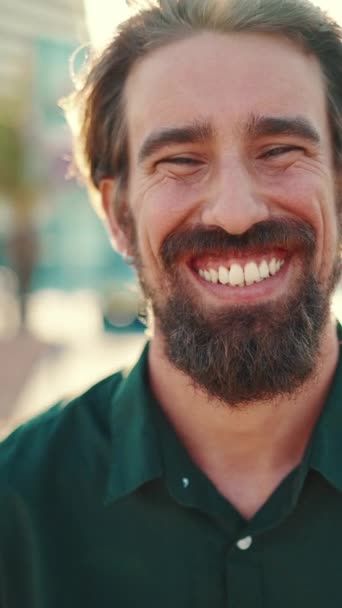 垂直录像 一个带着胡子的微笑男子在城市背景上的特写 快乐的年轻嬉皮士男性在镜头前的近照 — 图库视频影像