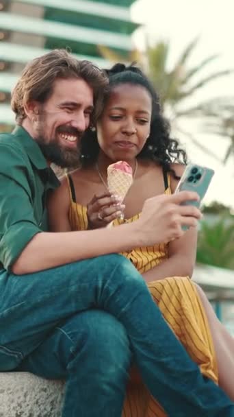 アダルトビデオ スマホで動画を見ている幸せそうな男と笑顔の女のクローズアップ 都市の背景に携帯電話で楽しい若い異人種間カップルのブラウジング写真のクローズアップ — ストック動画