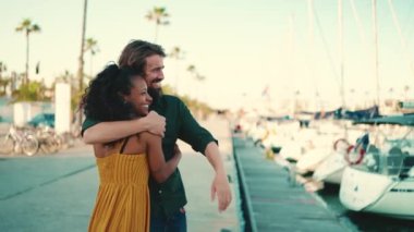 Genç mutlu erkek ve kadının, yat arka planında sevinçle kucaklaşmalarının yakın çekimi. Genç, ırklar arası bir çiftin yakın, neşeli randevusu..