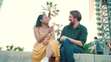 Şehirli arka planda dondurma yiyen, ırklar arası gülümseyen çiftlerin yakın çekimi. Dondurma tatmakta olan bir kadın ve erkeğin yakın çekimi.