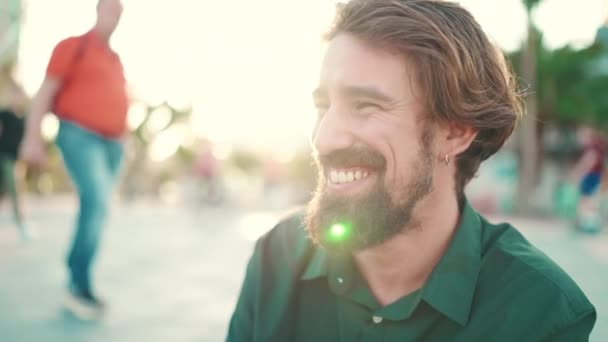 在城市背景上 一个留着胡子 手里拿着冰激凌的笑脸男子的特写 在一个温暖的阳光灿烂的日子里 一个快乐的年轻嬉皮士男子在冰淇淋测试中的前部特写 — 图库视频影像