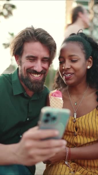 アダルトビデオ スマホで動画を見ている幸せそうな男と笑顔の女性のポートレートを閉じます 都市の背景に携帯電話で楽しい若い異人種間カップルのブラウジング写真のクローズアップ — ストック動画