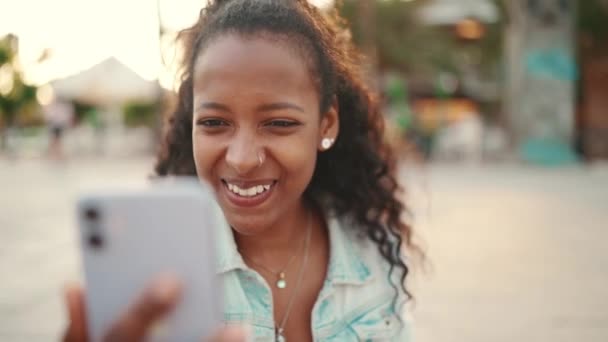 在城市背景下 用手机拍摄的长发女青年的肖像 在智能手机上发送语音讯息的女孩的特写 — 图库视频影像