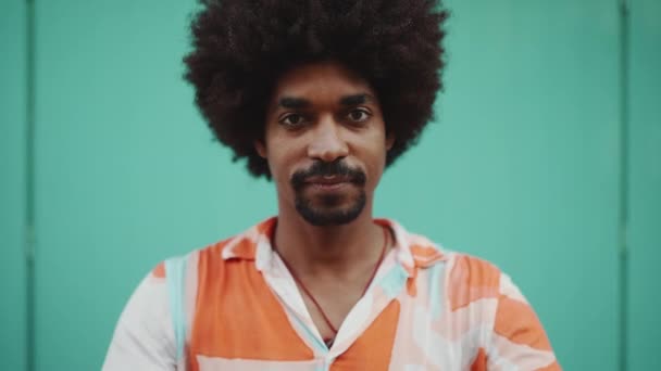在镜头前 年轻的非洲裔男子身穿衬衫 在浅蓝色的墙壁背景下对着相机微笑 生活方式的概念 慢动作 — 图库视频影像