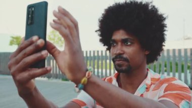 Gömlek giyen genç Afro-Amerikan 'ın yakın çekimlerinde akıllı telefon kullanılıyor. Yaşam tarzı konsepti. Yavaş çekim
