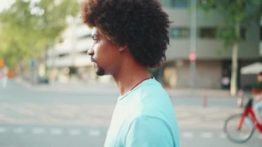Açık mavi tişörtlü genç Afro-Amerikan adamın yaya geçidinden karşıya geçerken yakın çekimi. Yaşam tarzı konsepti. yavaş çekim
