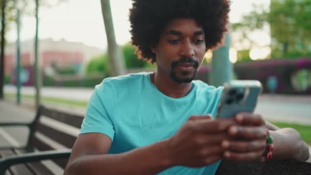 Feche Jovem Afro Americano Camiseta Azul Sentado Banco Parque Usando — Vídeo de Stock