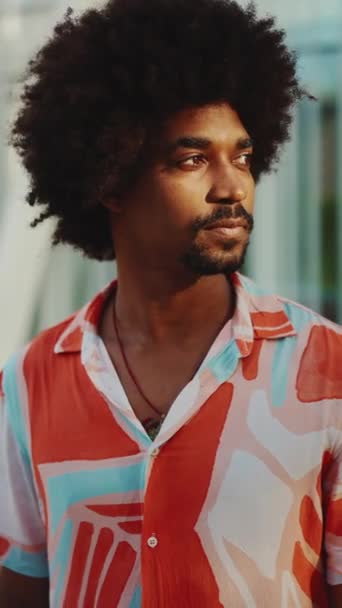 垂直ビデオ 都会の通りの背景にシャツを着た若いアフリカ系アメリカ人男性の笑顔のクローズアップ肖像画 ライフスタイルの概念 スローモーション — ストック動画