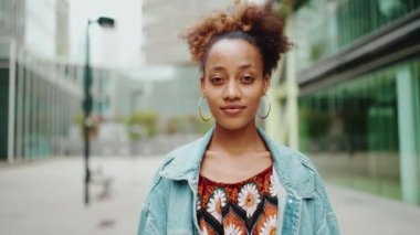 Kameraya gülümseyen Afrikalı bir kızın ön portresi. Yavaş çekim, kamera insana doğru ilerliyor.