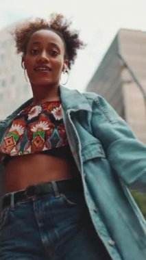 Kapalı çekim, at kuyruklu gülümseyen Afrikalı kız, at kuyruğu ceketli, tarlada milli şablon ile kulaklıkla müzik dinliyor ve açık havada dans ediyor. Yavaş çekim