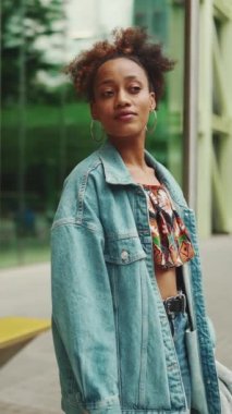 At kuyruklu, kot ceketli, ulusal desenli ekin giysili, otobüs durağında duran tatlı Afrikalı kız. Yavaş çekim